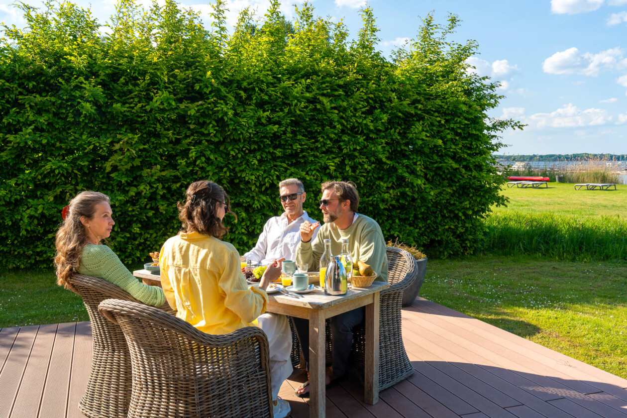 Vier Menschen sitzen am Tisch und frühstücken