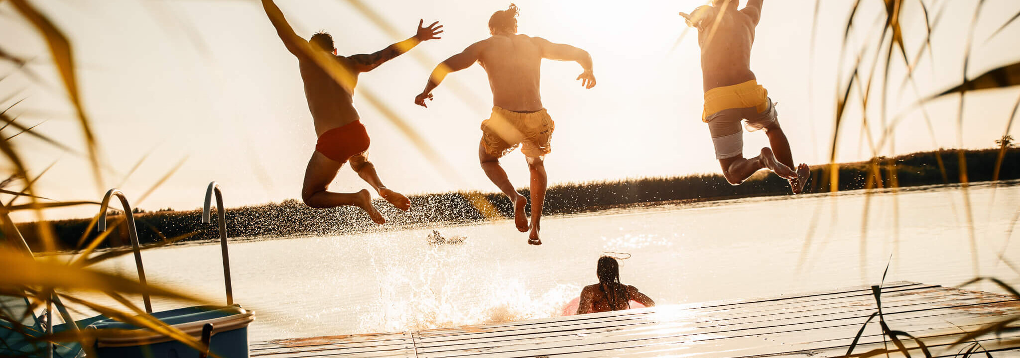 Drei Männer springen freudig in den See