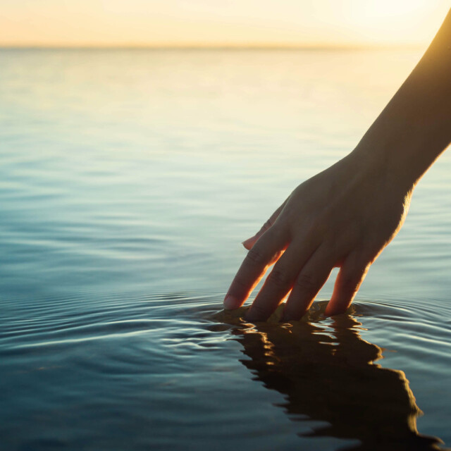 Hand gleitet durch das Wasser