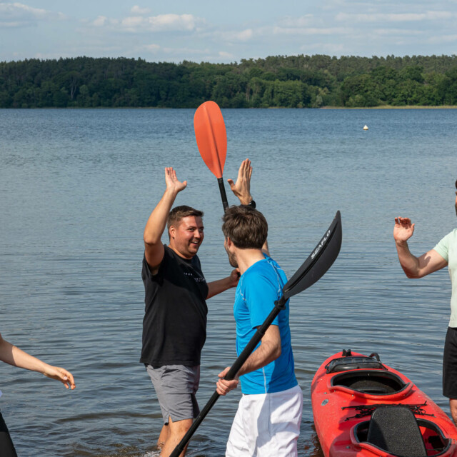 Vier Menschen klatschen sich in die Hände, Kajak, See