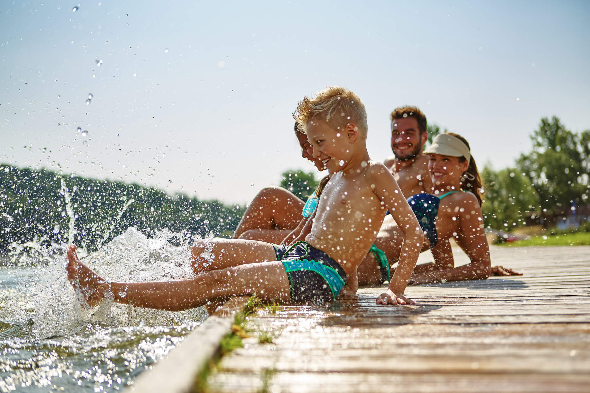 Eine Familie sitzt auf einem Steg am See